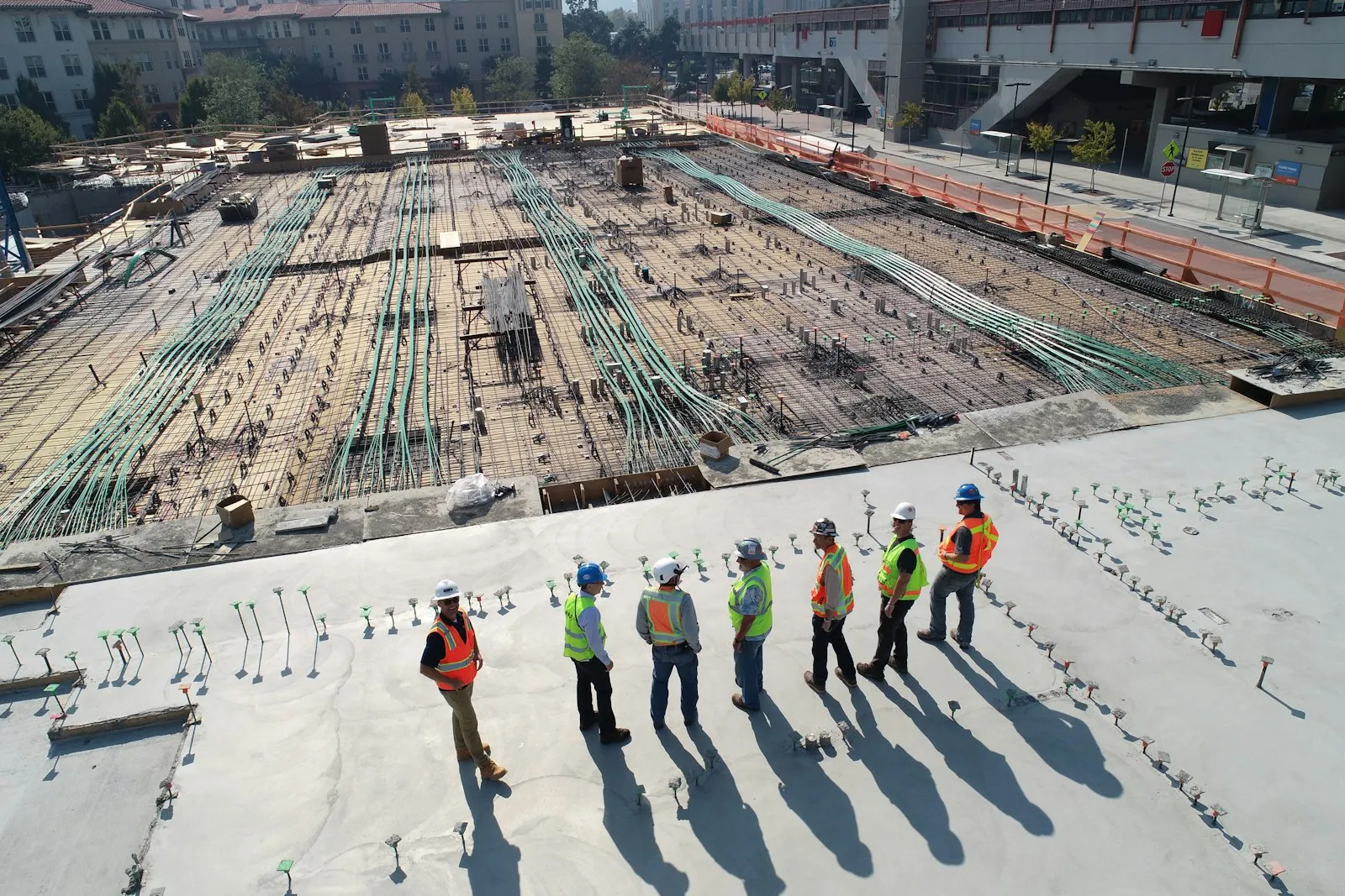 Construction crew standing on a freshly poured concrete deck above rebar and post-tension cables